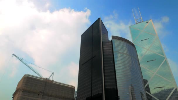 Hong Kong - Arranha-céus e construção com guindaste contra o céu. Resolução 4K acelera . — Vídeo de Stock