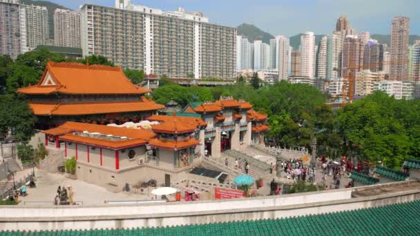 Hong Kong - Los visitantes que entran en el templo de Wong Tai Sin con bloque de pisos en el fondo. Vista aérea de resolución 4K. Acelera. . — Vídeo de stock