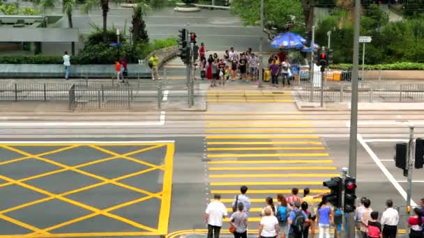 HONG KONG - Gente cruzando la calle en el centro de la ciudad con tranvías de dos pisos pasando. Velocidad de resolución 4K . — Vídeo de stock