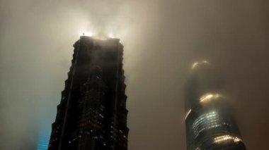 Şangay - Lujiazui, Pudong 'da bulutlarda saklanan gökdelenlerin gece manzarası. 4K çözünürlük zaman aşımı