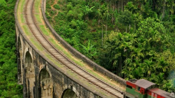Ella - Вид с воздуха на поезд на старый арочный мост в пышной холмистой сельской местности. Шри-Ланка. Разрешение 4K. — стоковое видео