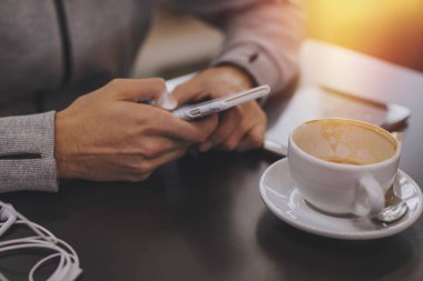 kafeteryada kahve fincan ile cep telefonu eller