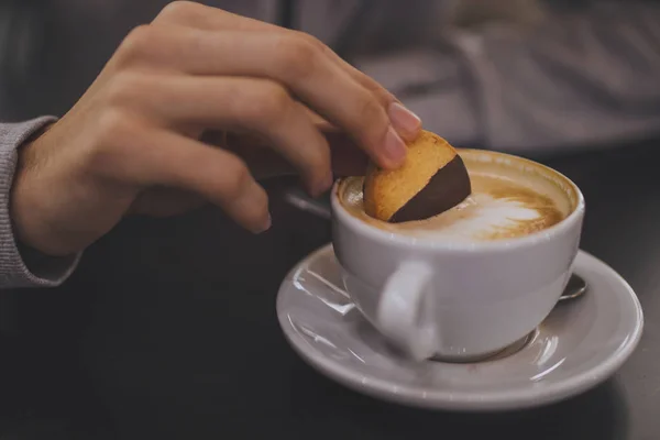 hand with biscuit in the cup of coffee, breakfast and snack