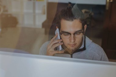 bilgisayar ve cep telefonu evde veya office çalışma ile genç adam