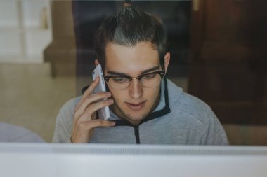 bilgisayar ve cep telefonu evde veya office çalışma ile genç adam