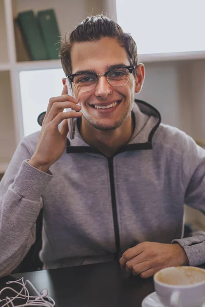 fashionable young man smiling with mobile phone and coffee mug