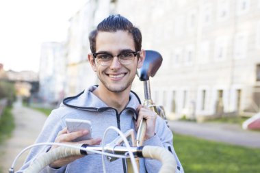 Genç bisikletçi ile cep telefonu ve şehirde bisiklet