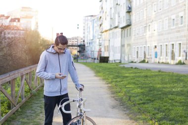 Genç bisikletçi ile cep telefonu ve şehirde bisiklet