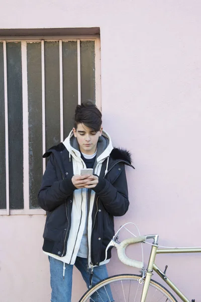 teenager with mobile phone and vintage bike on urban street