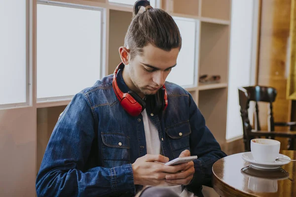 young man with headphones and phone in the cafeteria