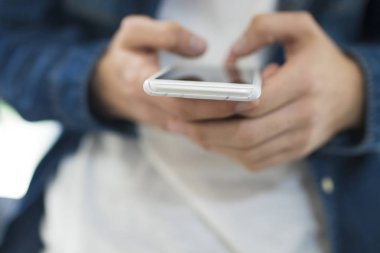 ön planda bir cep telefonu ile genç eller