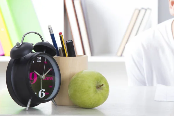 clock, pen and apple on studio desk