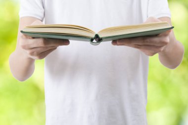 yeşil zemin üzerine açık kitap ile el