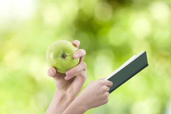 hands with apple and book