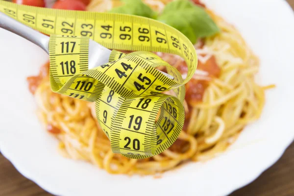 fork with tape measure and food background, diet concept