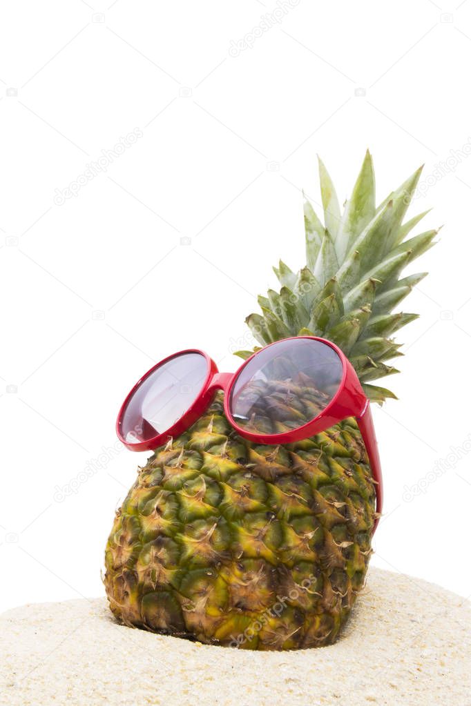pineapple with sunglasses in the summer landscape on the beach