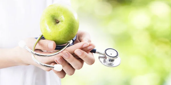 hands with Apple and stethoscope, healthy eating concept