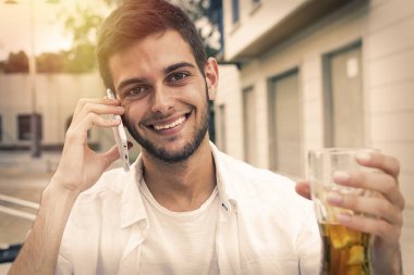 kafeterya veya barda içki ile cep telefonunda konuşan genç adam