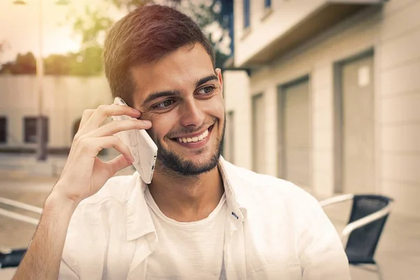 屋外の携帯電話と一緒に笑顔の若い男 — ストック写真