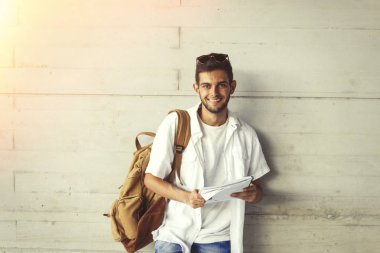 alt duvar kitap ve sırt çantası ile gülümseyen öğrenci portresi