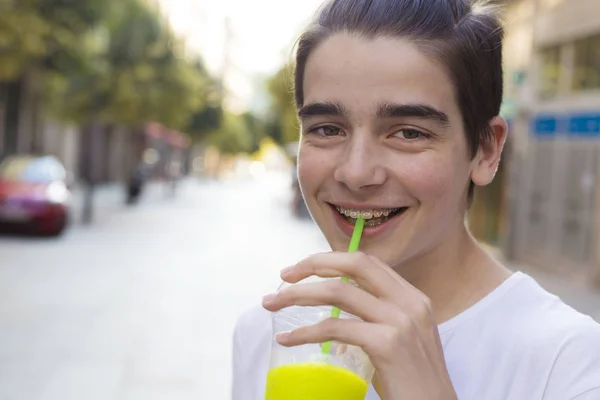 portrait of young teenager drinking soda on the street