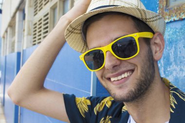 gülümseyen güneş gözlüğü ve şapka ile genç adam portresi