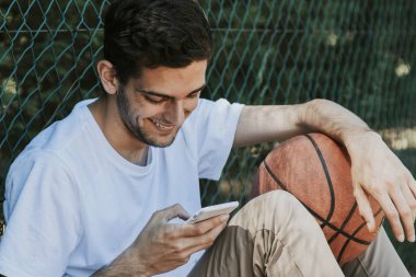 Genç gülen cep telefonu ve basketbol ile açık