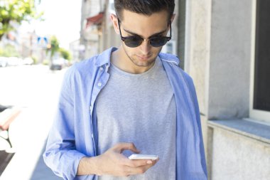 Genç adam sokakta yürürken cep telefonunuzla
