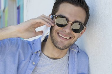 cep telefonu üzerinde konuşurken güneş gözlüklü genç portresi