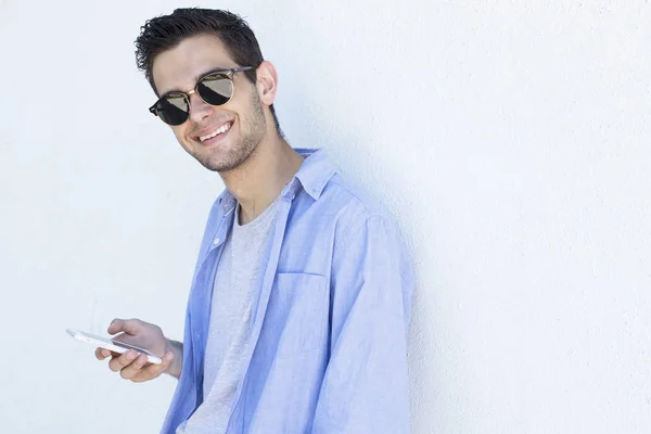 young man with mobile phone on the wall