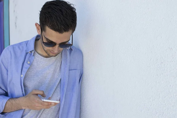 young man with mobile phone on the wall