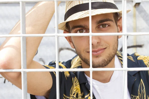portrait of a young man behind bars or fences