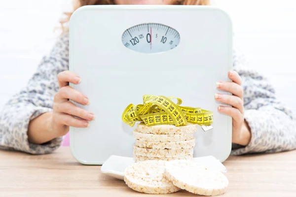 diet and slimming concept, corn cakes with tape measure and girl