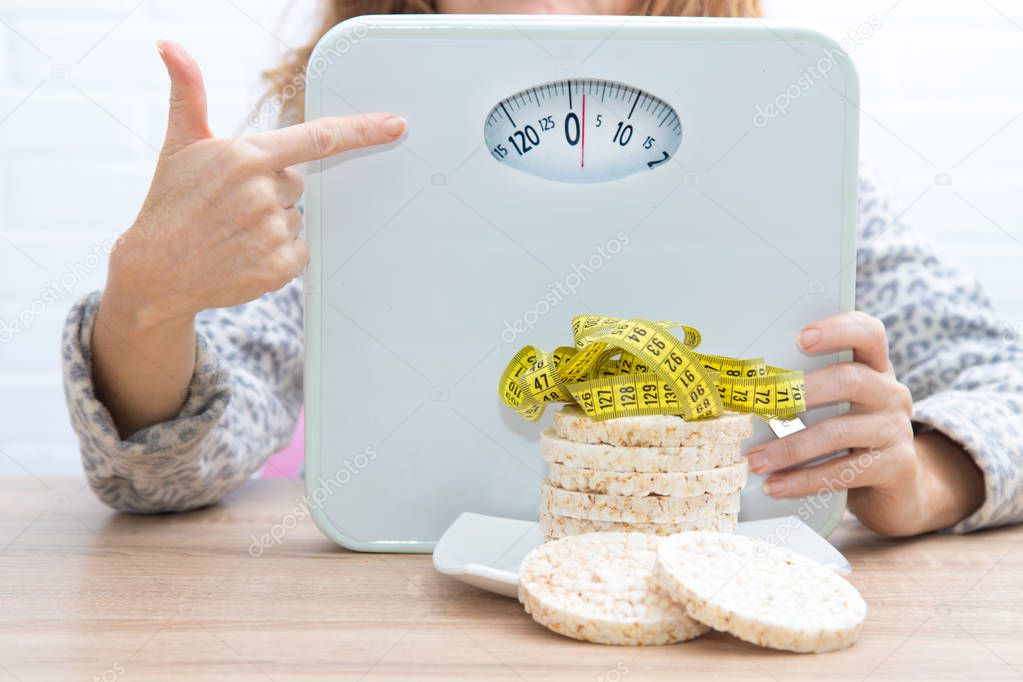 diet and slimming concept, corn cakes with tape measure and girl