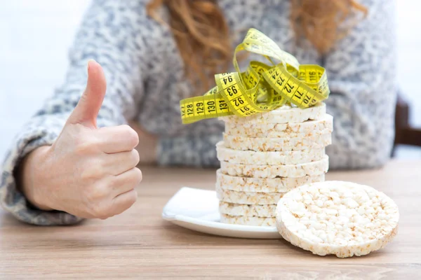 diet and slimming concept, corn cakes with tape measure and girl