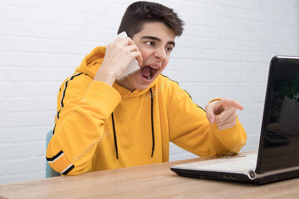 angry young man with mobile phone and laptop arguing or screaming