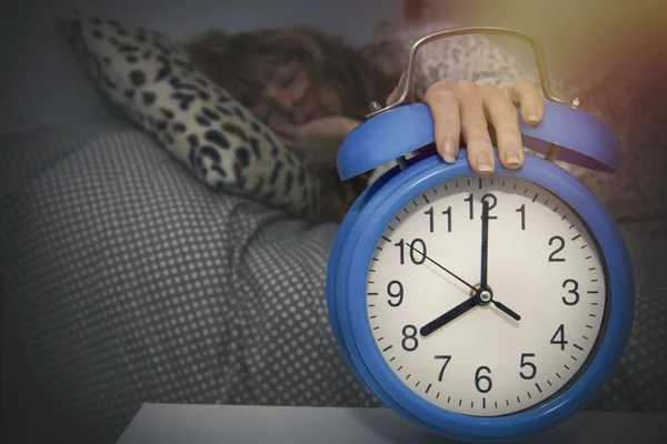 目覚まし時計で手で寝ている女性は — ストック写真