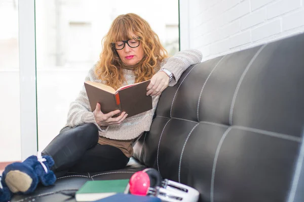 Donna Anziana Che Legge Libro Sul Divano — Foto Stock