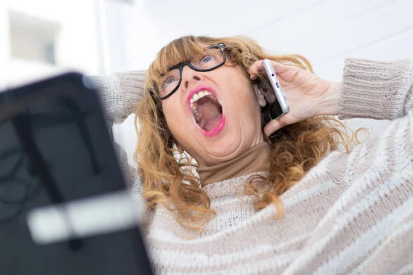 angry woman screaming with mobile phone and laptop
