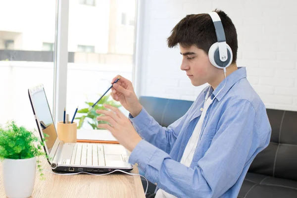 デスクトップ上のコンピュータとヘッドフォンを持つ十代の学生 — ストック写真