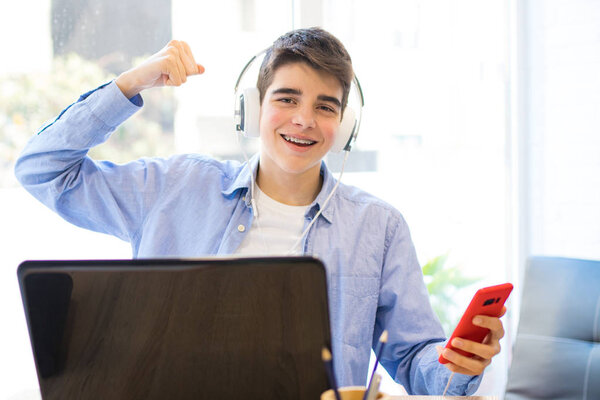 student or teenager celebrating success with laptop and phone