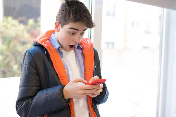 Zdumiony Młody Człowiek Ogląda Telefon Komórkowy — Zdjęcie stockowe