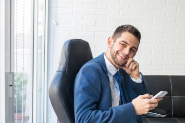 ofiste cep telefonu ile gülümseyen işadamı