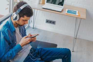 cep telefonu ve kulaklık ile evde adam