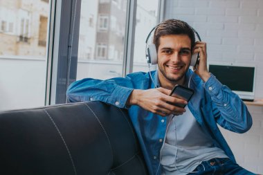 cep telefonu ve kulaklık ile evde adam