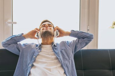 kulaklıkile evde müzik dinleyen genç adam