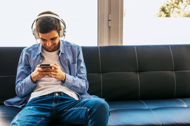 evde cep telefonu ve kulaklık ile genç adam veya genç