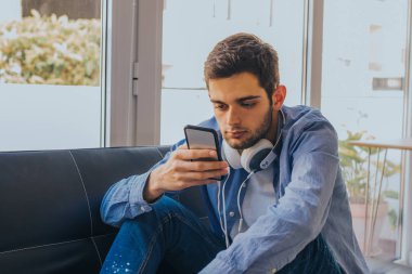 Evde cep telefonu olan genç bir adam.