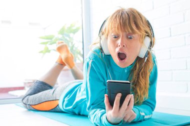 spor giyim kadın telefon ve kulaklık ile müzik dinlerken