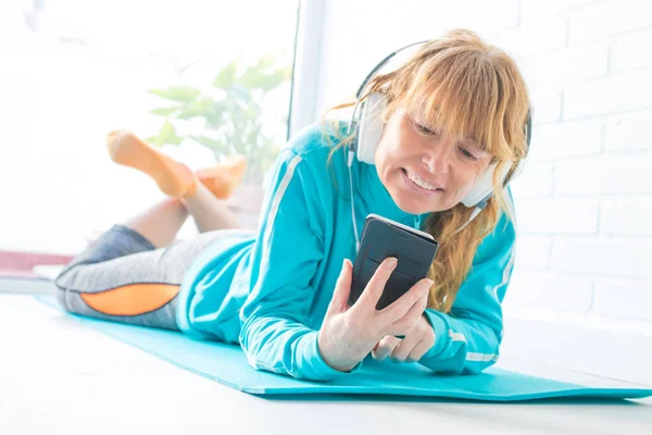 携帯電話とヘッドフォンで音楽を聴くスポーツウェアの女性 — ストック写真